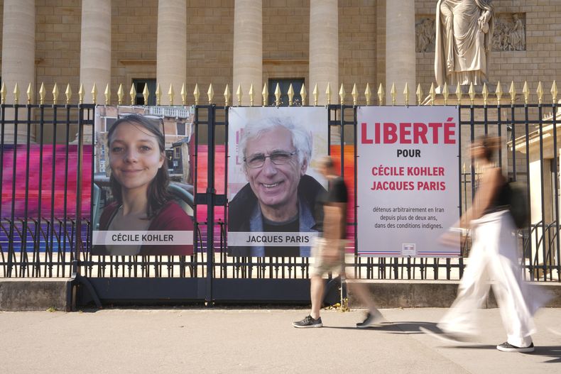 Los retratos de los ciudadanos franceses Cecile Kohler y Jacques Paris, encarcelados en Irán desde hace tres años, frente a la Asamblea Nacional en París el 3 de julio del 2025. (AP foto/Aurelien Morissard)