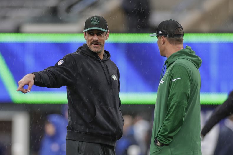 Aaron Rodgers, izquierda, y Zach Wilson, derecha, quarterbacks de los Jets de Nueva York intercambian palabras previo al calentamiento del equipo antes del partido de la NFL en contra de los Giants de Nueva York, el domingo 29 de octubre de 2023, en East Rutherford, Nueva Jersey. (AP Foto/Adam Hunger)