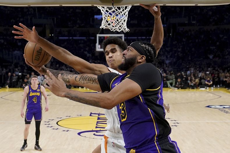 Anthony Davis, de los Lakers de Los Ángeles, salta hacia la cesta frente a Oso Ighodaro, de los Suns de Phoenix, el viernes 25 de octubre de 2024 (AP Foto/Eric Thayer)
