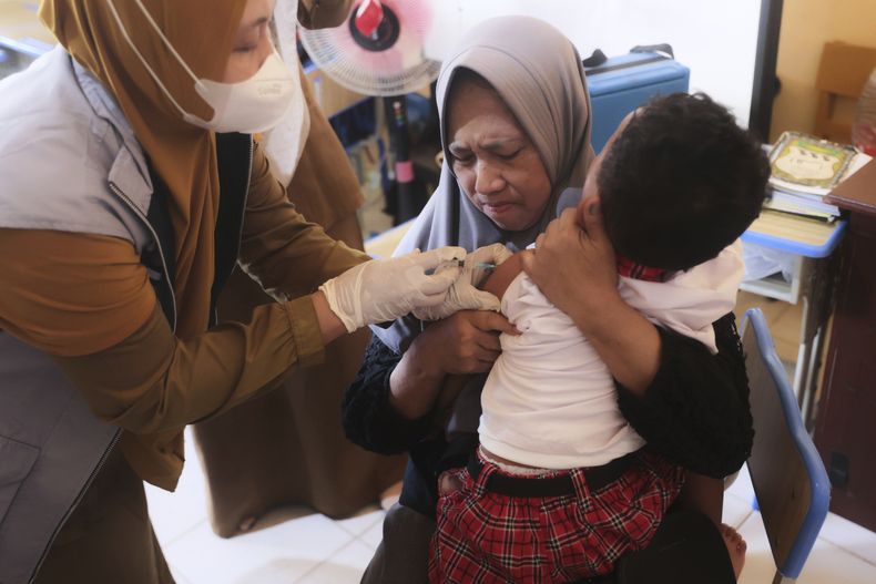 Un trabajador de salud pone una vacuna contra el sarampión a un niño durante una campaña de vacunación del sarampión tras un brote en Sumenep, Java Oriental, Indonesia, el lunes 25 de agosto de 2025. (AP Foto/Trisnadi)