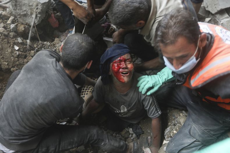 Un niño palestino herido llora mientras los rescatistas tratan de sacarlo de los escombros de un edificio derrumbado tras un ataque aéreo israelí en el campo de refugiados de Bureij, en la Franja de Gaza, el jueves 2 de noviembre de 2023. (AP Foto/Mohammed Dahman)