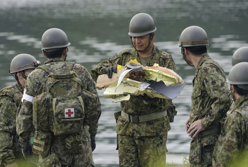 Un miembro de las Fuerzas de Autodefensa de Japón sostiene objetos que se cree son restos de un avión de entrenamiento de la Fuerza Aérea de Autodefensa, recuperados de un embalse en Inuyama, Japón, el jueves 15 de mayo de 2025, tras el desplome de la aeronave el miércoles. (Koji Harada/Kyodo News vía AP)