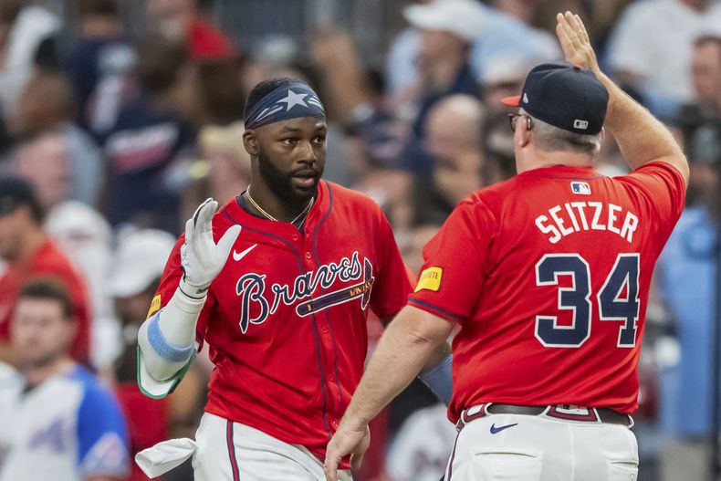 Michael Harris II, izquierda, de los Bravos de Altanta, recibe una felicitación del coach de bateo Kevin Seitzer (34) después de batear para la carrera de la victoria en la 10ma entrada en el juego de béisbol en contra de los Nacionales de Washington, el viernes 23 de agosto de 2024, en Atlanta. (AP Foto/Jason Allen)