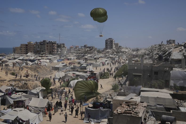 Palestinos corren para recoger ayuda humanitaria lanzada con paracaídas desde el aire, en la Ciudad de Gaza, en el norte de la Franja de Gaza, el 7 de agosto de 2025. (AP Foto/Jehad Alshrafi)