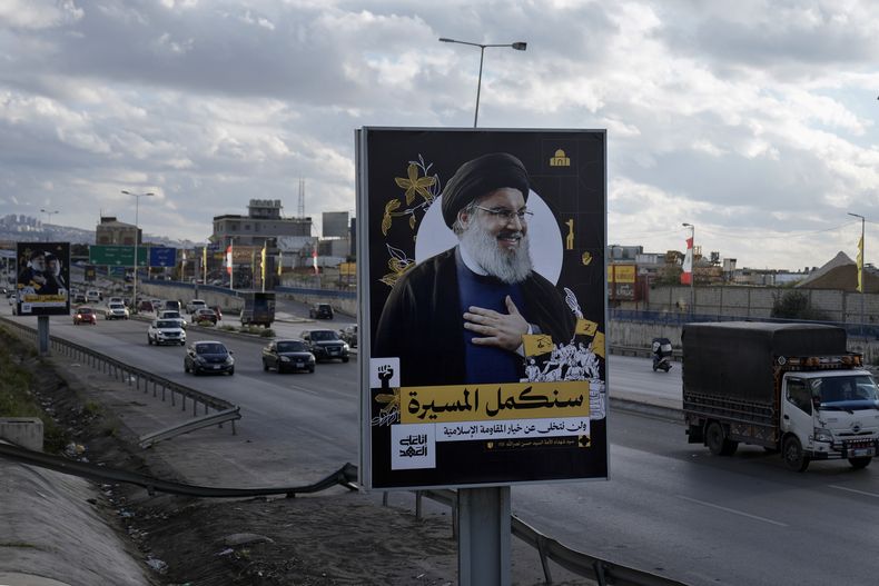 Varias personas pasan junto a una valla publicitaria con una imagen del difunto líder de Hezbollah, Sayyed Hassan Nasrallah, en la autopista del aeropuerto de Beirut, Líbano, viernes 21 de febrero de 2025. (AP foto/Bilal Hussein)
