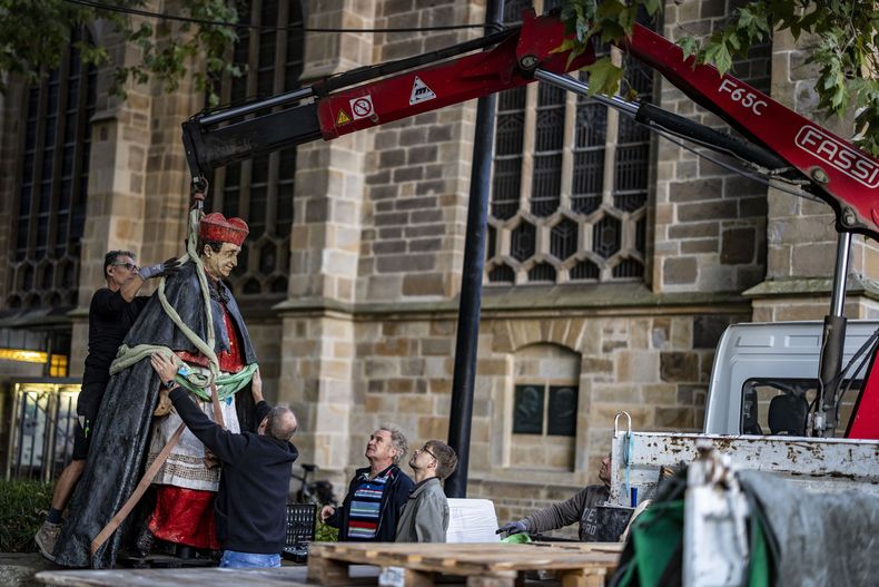 La escultura del cardenal de Essen Franz Hengsbach se ve alzada por una grúa ante la catedral de Essen durante el proceso de retirarla y cargarla en un camión en Essen, Alemania, el lunes 25 de septiembre de 2023. La estatua de un cardenal alemán fallecido fue retirada el lunes de su pedestal ante la catedral de Essen, en el oeste de Alemania, días después de que se hicieran públicas las acusaciones de abusos sexuales hace décadas. (Christoph Reichwein/dpa via AP)