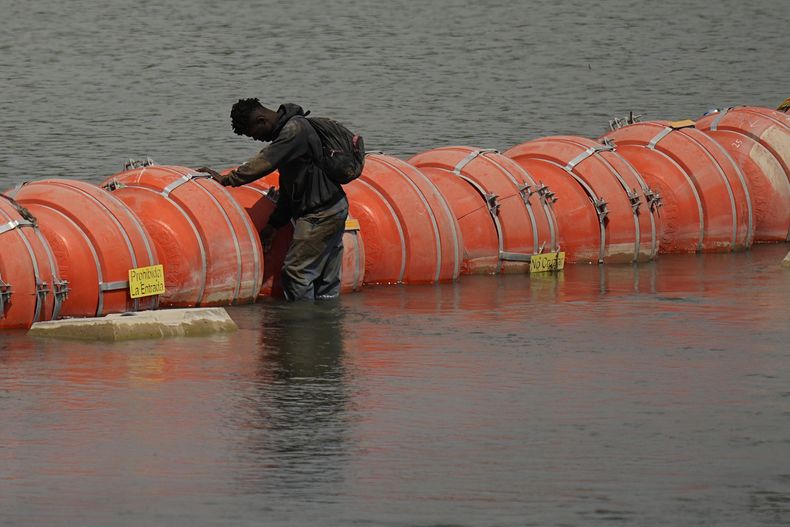 Un migrante colombiano frente a la barrera flotante de boyas mientras trata de cruzar el río Bravo (Grande) de México a Estados Unidos, el lunes 21 de agosto de 2023, en Eagle Pass, Texas. (AP Foto/Eric Gay)
