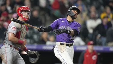 El venezolano Harold Castro, de los Rockies de Colorado, conecta un doble de dos anotaciones en la séptima entrada del partido contra los Rojos de Cincinnati en Denver, el lunes 15 de mayo de 2023. A la izquierda, el receptor de los Rojos, Tyler Stephenson. (AP Foto/David Zalubowski)