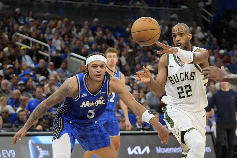 El escolta de los Bucks de Milwaukee Khris Middleton (22) pasa la bola ante el escolta del Magic de Orlando Paolo Banchero (5), durante la primera mitad del juego de baloncesto de la NBA, el domingo 14 de abril de 2024, en Orlando, Florida. (AP Foto/John Raoux)