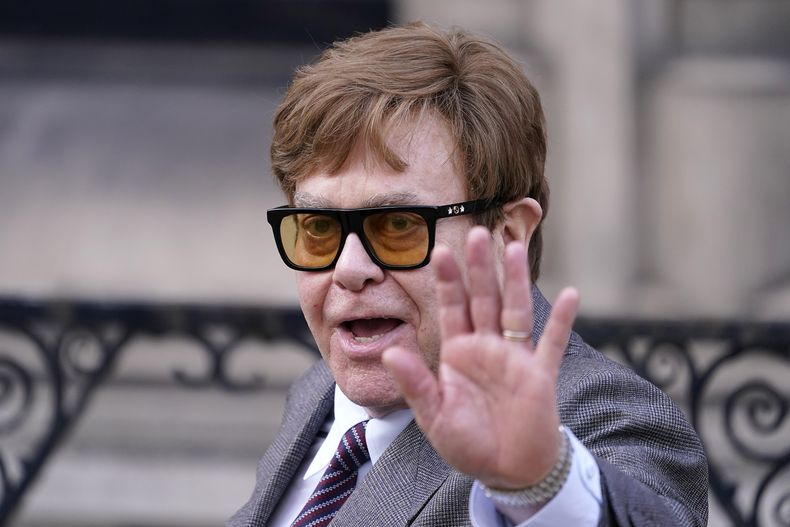 ARCHIVO - Elton John saluda a los medios de comunicación que esperan cuando sale de los Tribunales Reales de Justicia de Londres, el lunes 27 de marzo de 2023. (Foto AP/Alberto Pezzali, archivo)