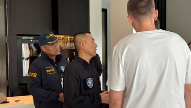 Un presunto hacker ruso de 35 años, identificado por la prensa rusa como Denis Obrezko (derecha, de espaldas), junto a agentes de la policía tailandesa tras haber sido detenido en Phuket, Tailandia, el 6 de noviembre de 2025. (Oficina de Investigación de Ciberdelitos de Tailandia vía AP)