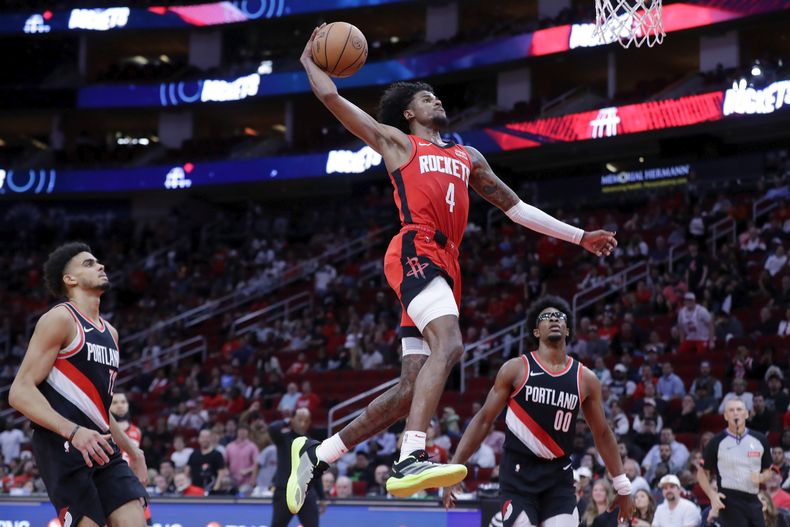 Jalen Green (4), de los Rockets de Houston, clava el balón entre Rayan Rupert, izquierda, y Scoot Henderson (00), de los Trail Blazers de Portland, durante la segunda mitad del juego de baloncesto de la NBA, el lunes 25 de marzo de 2024, en Houston. (AP Foto/Michael Wyke)