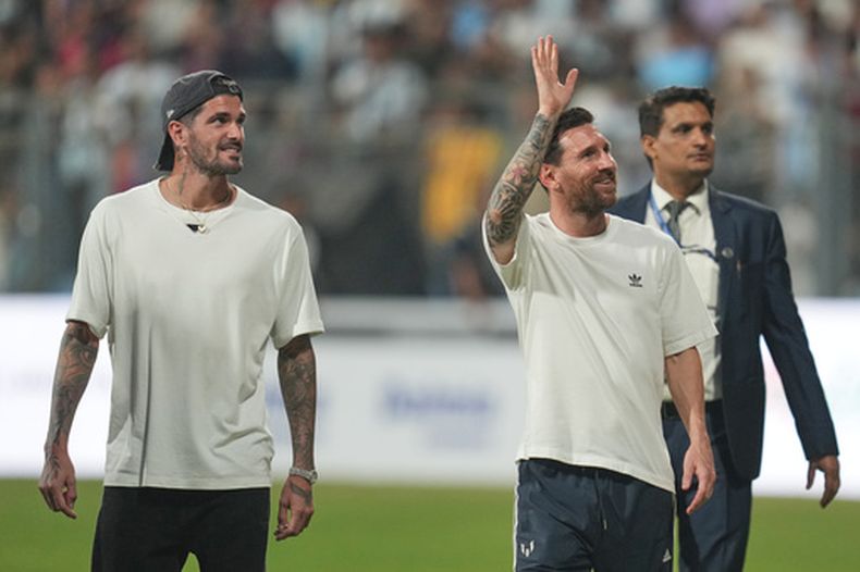 Los jugadores argentinos Lionel Messi y Rodrigo De Paul saludan al público en Mumbai, India, el domingo 14 de diciembre de 2025. (AP Foto/Rafiq Maqbool)