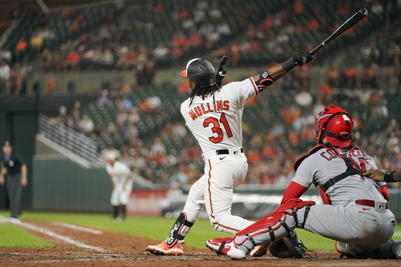 Cedric Mullins (31), de los Orioles de Baltimore, sigue su movimiento después de conectar ante la mirada del receptor de los Cardenales de San Luis, Willson Contreras, en lo que terminó como un grand slam ante el relevista Andre Pallante en la quinta entrada del juego de béisbol del lunes 11 de septiembre de 2023, en Baltimore. (AP Foto/Julio Cortez)