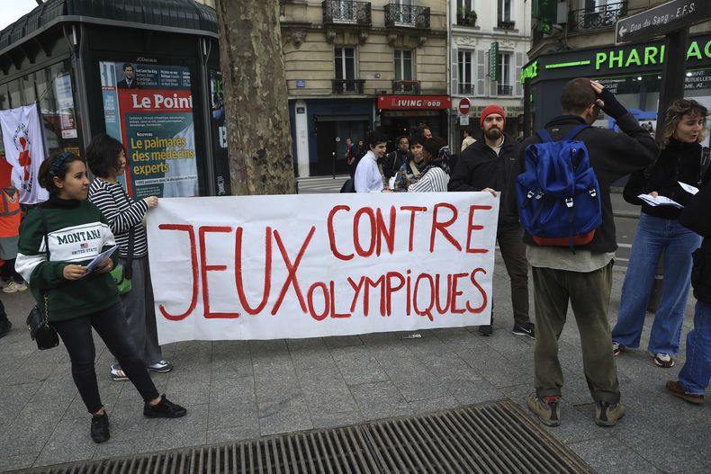 ARCHIVO - Activistas opuestos a las Olimpiadas de París de 2024 despliegan una manta que dice: Contra los Juegos Olímpicos, durante una manifestación el lunes 1 de mayo de 2023, en París. (AP Foto/Aurelien Morissard)