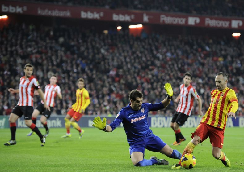 El jugador del Barcelona, Andr&eacute;s Iniesta, derecha, intenta pasar el bal&oacute;n frente al arquero del Athletic de Bilbao en un partido por la liga espa&ntilde;ola el domingo, 1 de diciembre de 2013, en Bilbao. (AP Photo/Alvaro Barrientos)