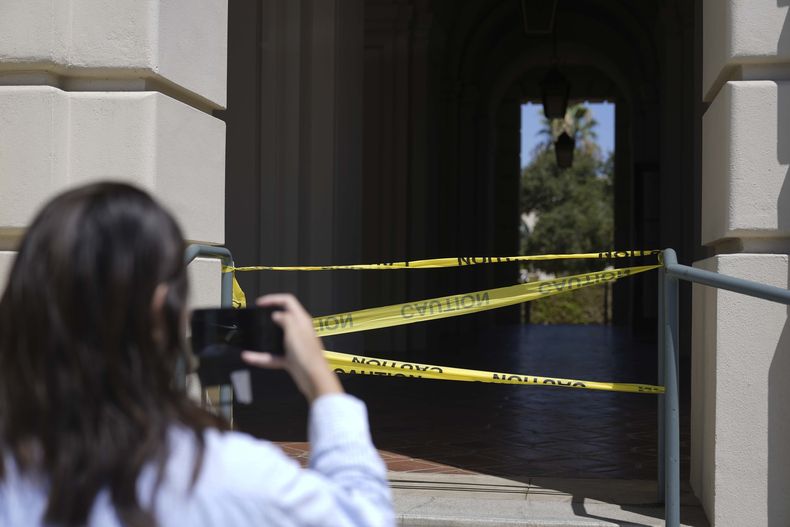 Una mujer toma una fotografía de una parte acordonada por la policía del Ayuntamiento de Pasadena, el lunes 12 de agosto de 2024, en Pasadena, California, tras un sismo de magnitud 4,4. (AP Foto/Ryan Sun)