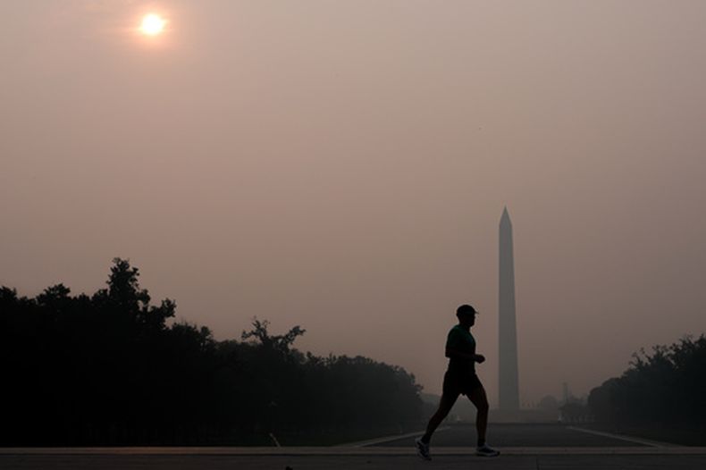 El sol queda oculto por el humo de los incendios forestales mientras una persona corre frente al Monumento a Washington, el 17 de julio de 2026, en el National Mall de Washington. (Foto AP/Julia Demaree Nikhinson)