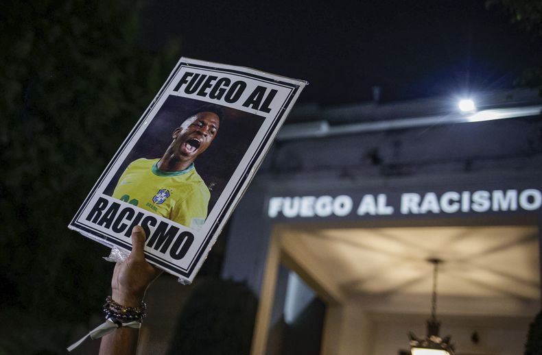 ARCHIVO - En foto del 23 de mayo del 2023, un manifestante sostiene una imagen del futbolista brasileño Vinicius Junior con un mensaje en portugués que se traduce: Pelea contra el racismo durante una manifestación por el racismo contra el jugador. (AP Foto/Tuane Fernandes, Archivo)