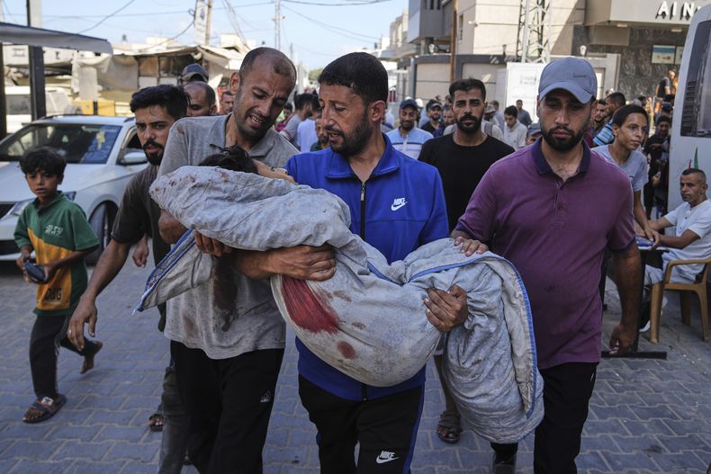Parientes llevan el cuerpo de Seraje Ebrahim, de 13 años, asesinado en un ataque israelí a un punto de distribución de agua ante el hospital de Al-Awda en Nuseirat, en el centro de la Franja de Gaza, el domingo 13 de julio de 2025. (AP Foto/Abdel Kareem Hana)