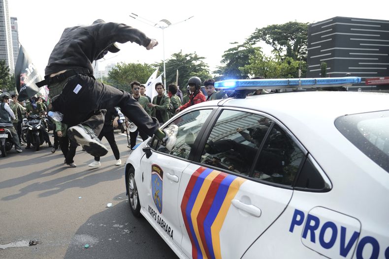 Un estudiante ataca un coche de la policía durante una protesta tras la muerte de un repartidor atropellado por un vehículo policial blindado en una manifestación contra los privilegios de los legisladores, en Yakarta, Indonesia, el 29 de agosto de 2025. (AP Foto/Tatan Syuflana)