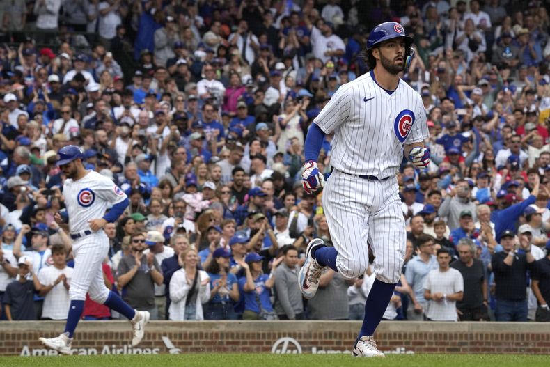 Dansby Swanson (derecha) de los Cachorros de Chicago avanza hacia primera base, mientras que Mike Tauchman (al fondo izquierdo) anota durante la tercera entrada ante los Bravos de Atlanta, en Chicago. Doming 6 de agosto de 2023 (AP Foto/Nam Y. Huh)