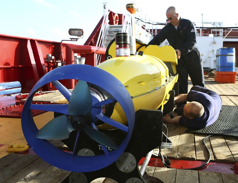 Foto del 17 de abril del 2014 de la Fuerza de Defensa Australiana de los empleados Evan Tanner, fondo a la derecha, y Chris Minor, de Phoenix International, inspeccionando el submarino Artemis en la cubierta del buque australiano Ocean Shield, para buscar