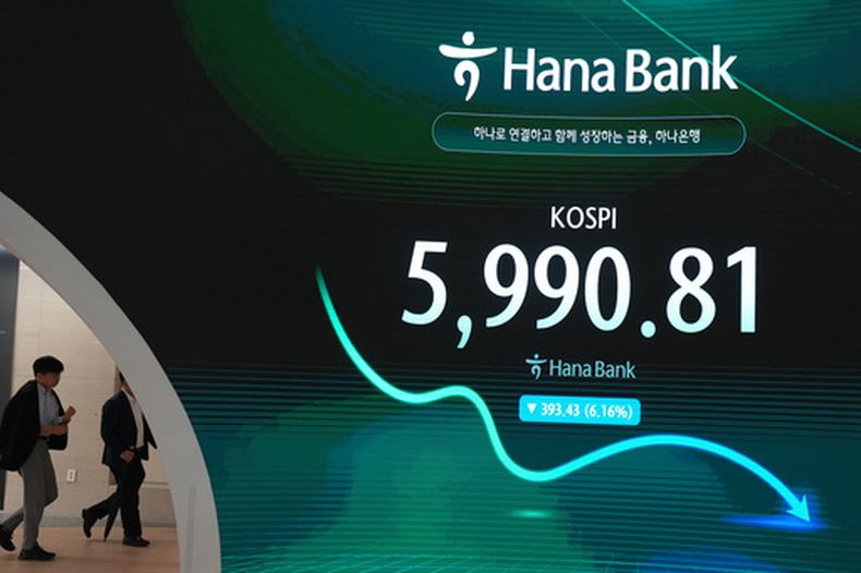 Dos operadores pasan frente a la pantalla que muestra el Índice Compuesto de Precios de Acciones de Corea (KOSPI) en una sala de operaciones del Hana Bank, el martes 13 de octubre de 2026, en Seúl, Corea del Sur. (AP Foto/Lee Jin-man)
