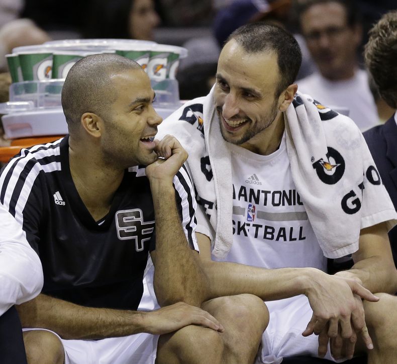 El argentino Manu Gin&oacute;bili (derecha) r&iacute;e en el banquillo con el franc&eacute;s Tony Parker, durante el partido entre los Spurs de San Antonio y los Pelicans de Nueva Orle&aacute;ns, el lunes 25 de noviembre de 2013 (AP Foto/Eric Gay)