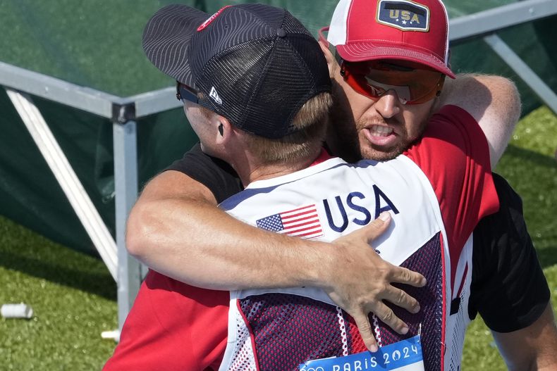 El estadounidense Vincent Hancock abraza a su compatriota Conner Lynn Prince, luego que ambos ganaron el oro y la plata, respectivamente, en la modalidad de skeet del tiro olímpico, el sábado 3 de agosto de 2024, en Chateauroux, París (AP foto/Manish Swarup)