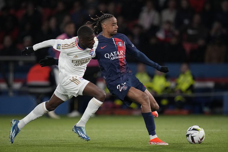 Clinton Mata del Lyon pelea por el balón con Bradley Barcola del Paris Saint-Germain en el encuentro de liga del domingo 21 de abril del 2024. (AP Foto/Christophe Ena)