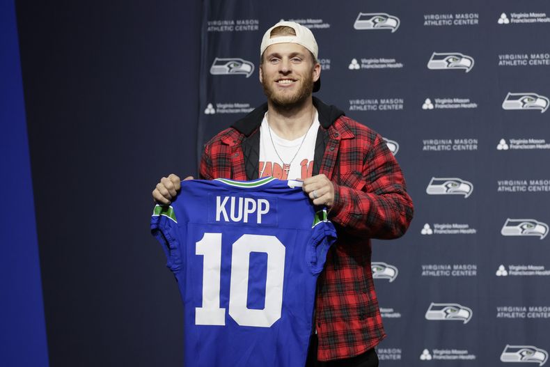 El receptor de los Seahawks de Seattle Cooper Kupp sostiene el jersey con su número 10 durante la conferencia de prensa de su presentación el martes 18 de marzo del 2025. (AP Foto/John Froschauer)
