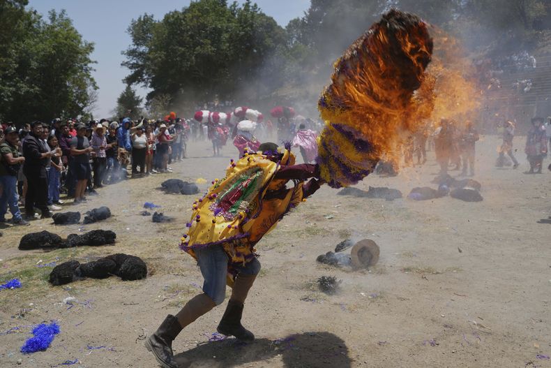 Un personaje llamado sayón intenta apagar el fuego que encendió en su sombrero de pañuelos de papel dentro de las celebraciones de la Pascua, el domingo 20 de abril de 2025, en Tetela del Volcán, México. (AP Foto/Eduardo Verdugo)