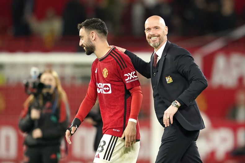 El técnico del Manchester United Erik ten Hag camina hacia el campo con el jugador Bruno Fernandes tras la victoria ante el Newcastle en la Liga Premier el miércoles 15 de mayo del 2024. (AP Foto/Dave Thompson)