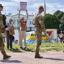 Miembros de la Guardia Nacional patrullan Lafayette Park cerca de la Casa Blanca, el viernes 29 de agosto de 2025, en Washington, mientras que el manifestante Will Roosien, de Grand Rapids, Michigan, que pretende inspirar a otras personas de su generación para que protesten, sostiene un cartel sobre el movimiento MAGA. (AP Foto/Jacquelyn Martin)