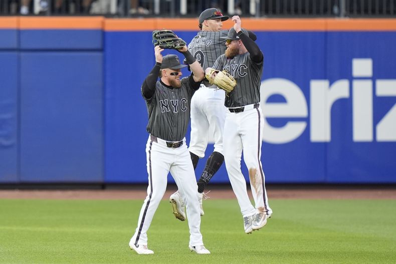 Harrison Bader, a la izquierda, Brandon Nimmo, al centro, y Ben Gamel, a la derecha, de los Mets de Nueva York, celebran tras vencer a los Rockies de Colorado, el sábado 13 de julio de 2024, en Nueva York. Los Mets ganaron 7-3. (AP Foto/Frank Franklin II)