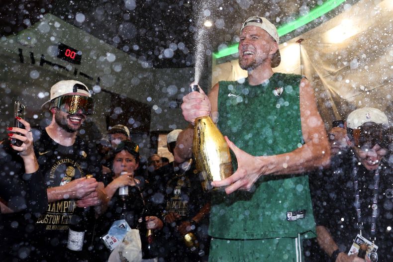 El pívot letón Kristaps Porzingis, de los Celtics de Boston, arroja champaña durante la celebración de la victoria sobre los Mavericks de Dallas en el quinto partido de las Finales de la NBA, el lunes 17 de junio de 2024 (Elsa/Pool Foto via AP)