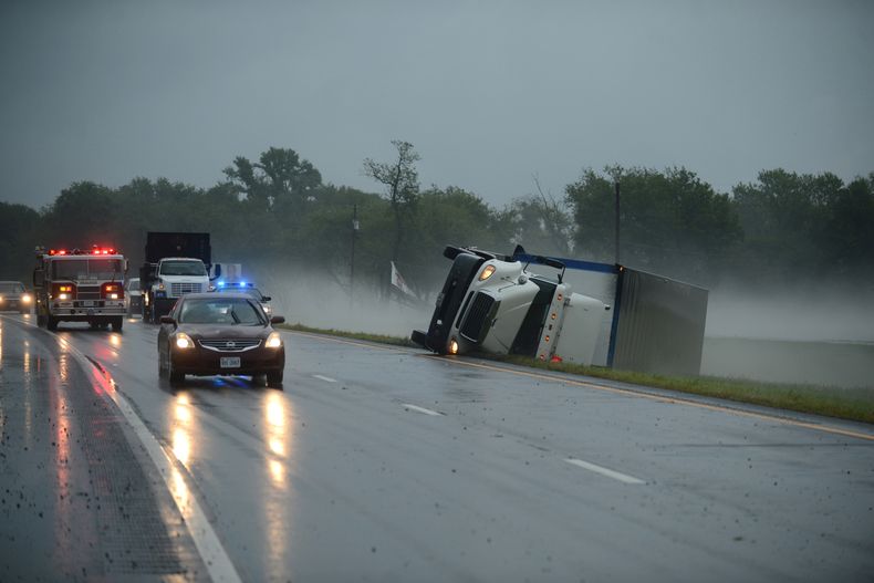 Veh&iacute;culos de rescate pasan junto a un cami&oacute;n de carga volcado a consecuencia de de los vientos provocados por una tormenta en Cheriton, Virginia, que caus&oacute; dos muertes el jueves 24 de julio de 2014. (Foto de AP/Eastern Shore News, Jay