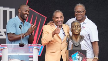 El exjugador de la NFL Roger Craig, al centro, devela su busto junto a su hijo, Roderick Craig, a la izquierda, y Jamie Williams durante la ceremonia de inducción al Salón de la Fama del Fútbol Americano Profesional en el Salón de la Fama del Fútbol Americano Profesional, en Canton, Ohio, el sábado 8 de agosto de 2026. (Foto AP/Sue Ogrocki)
