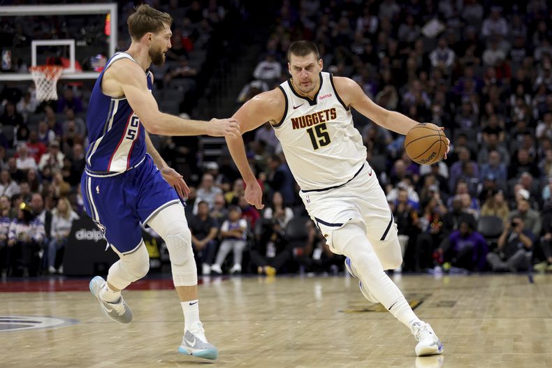 El jugador de los Nuggets de Denver Nuggets Nikola Jokic (con el 15) se dirige a canasta ante el jugador de los Kings de Sacramento Domantas Sabonis, a la izquierda, en la primera mitad de su juego de NBA en Sacramento, California, el sábado 2 de diciembre de 2023. (AP Foto/Jed Jacobsohn)