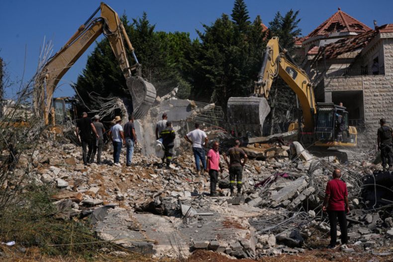 Gente mira a trabajadores de rescate utilizando excavadoras mientras buscan víctimas bajo los escombros de un edificio destruido en un ataque aéreo israelí en el poblado de Kfar Rumman, Líbano, el lunes 7 de septiembre de 2026. (AP Foto/Mohammed Zaatari)