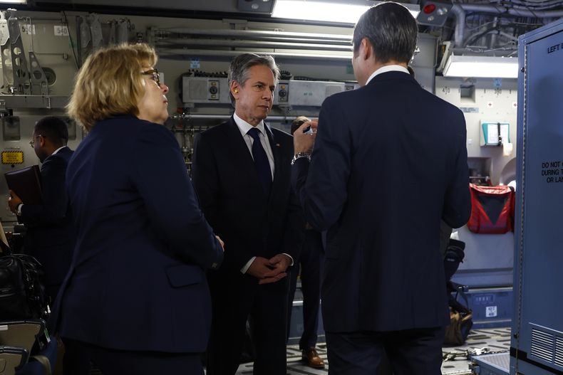 El secretario de Estado de Estados Unidos, Antony Blinken (centro), habla con dos personas en un C-17 Globemaster antes de despegar hacia El Cairo, Egipto, en Yeda, Arabia Saudí, el 21 de marzo de 2024. (Evelyn Hockstein/Pool Foto vía AP)