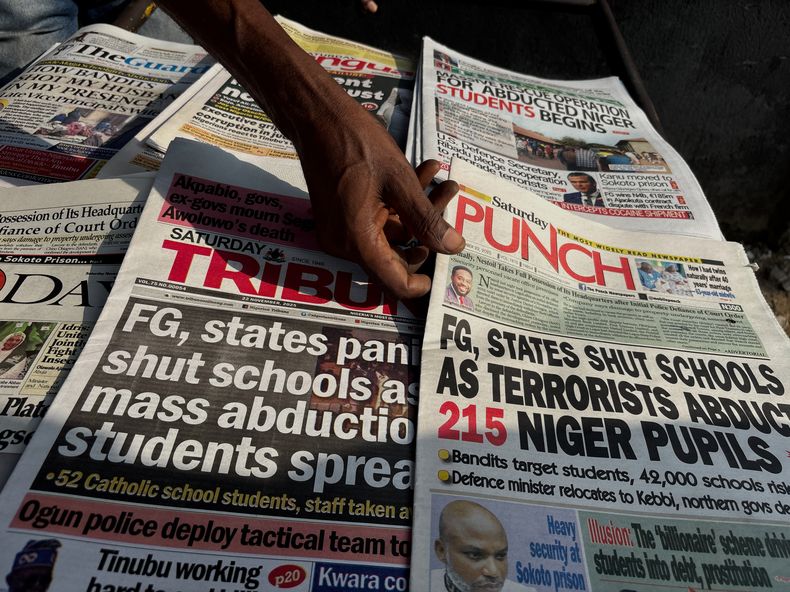 Un vendedor callejero muestra las portadas de los diarios, que recogen el secuestro de estudiantes de la escuela católica St. Mary, el 22 de noviembre de 2025, en Lagos, Nigeria. (AP Foto/Sunday Alamba )