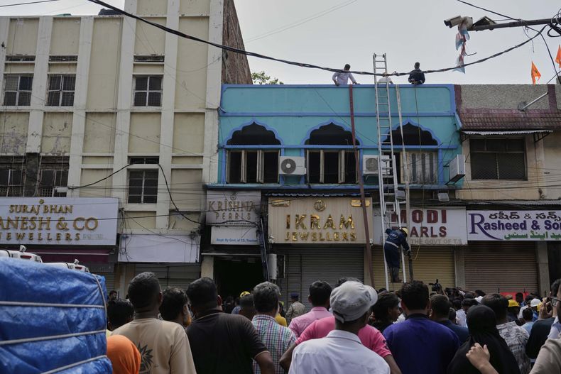 Gente mirando mientras bomberos realizan tareas de rescate en un edificio tras un incendio en Hyderabad, India, el domingo 18 de mayo de 2025. (AP Foto/Mahesh Kumar A.)