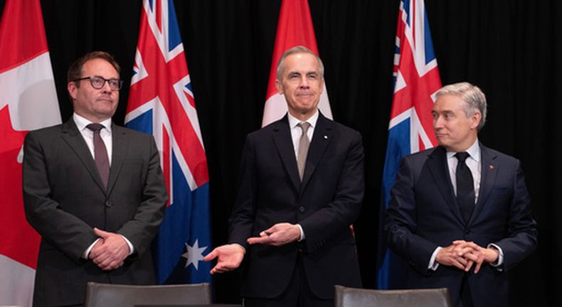 El primer ministro de Canadá, Mark Carney (centro), hace un gesto a Daniel Mulino, ministro australiano de Tesoro, durante su presentación al inicio de la firma de un documento, ante la mirada del ministro de Finanzas canadiense, François-Philippe Champagne (derecha), en Sydney, Australia, el 4 de marzo de 2026. (Adrian Wyld/The Canadian Press via AP)