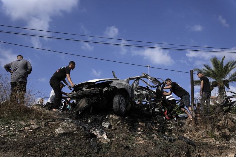 Palestinos se acercan a un auto destruido por el ataque de un dron en la localidad de Zeita, al norte de la ciudad cisjordana de Tulkarem, el 3 de agosto de 2024. (AP Foto/Majdi Mohammed)