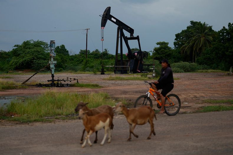 Un hombre pasa en bicicleta junto a una bomba de petróleo en funcionamiento en Cabimas, Venezuela, el lunes 31 de agosto de 2026. (AP Foto/Ariana Cubillos)