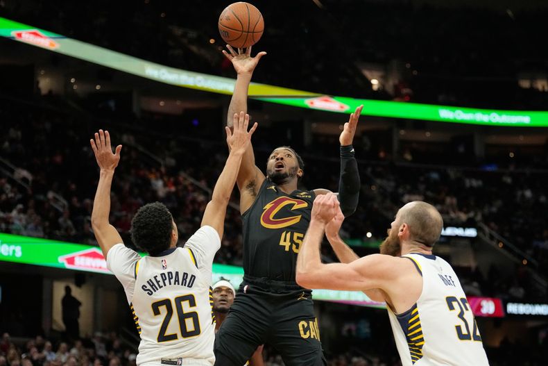 Donovan Mitchell (45), de los Cavaliers de Cleevland, dispara entre Ben Sheppard (26) y Jay Huff (32), de los Pacers de Indiana, en la segujnda mitad del juego de baloncesto de la Copa NBA, el viernes 21 de noviembre de 2025, en Cleveland. (AP Foto/Sue Ogrocki)