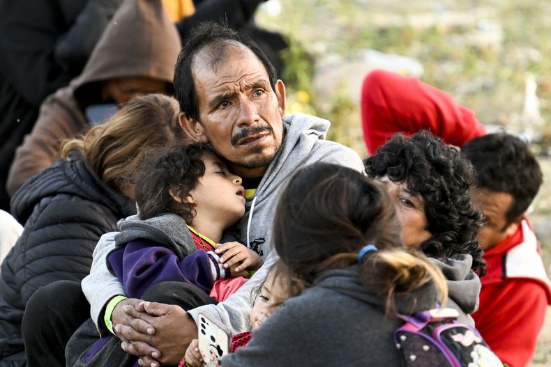 Solicitantes de asilo esperan entre la doble barda en territorio estadounidense a lo largo de la frontera entre Estados Unidos y México, cerca de Tijuana, México, el lunes 8 de mayo de 2023, en San Diego. Los migrantes aguardan a ser procesados por la Patrulla Fronteriza. (AP Foto/Denis Poroy)