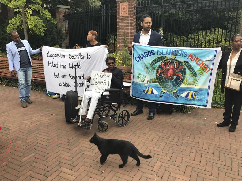 ARCHIVO - Manifestantes sostienen carteles ante la Corte Mundial en La Haya, Holanda, el lunes 3 de septiembre de 2018, donde los jueces escuchan argumentos en un caso sobre si Reino Unido mantiene una soberanía ilegal sobre las islas Chagos. (AP Foto/Mike Corder, Archivo).